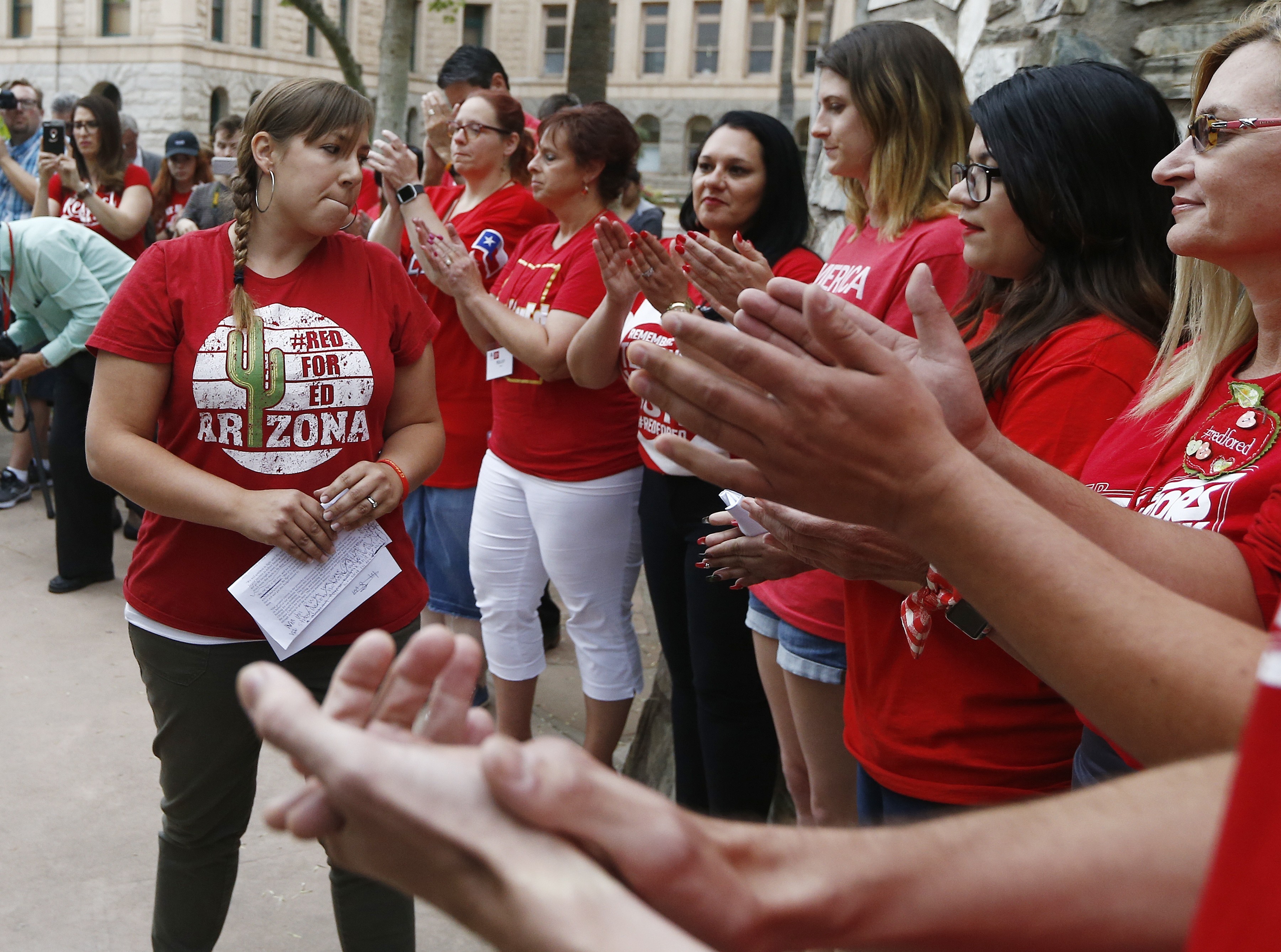 Phoenix teacher Rebecca Garelli, left, an Arizona Educators United member, is applauded after her announcement from protest organizers that teachers intend to go back to work as the statewide teachers strike enters a fourth day at the Arizona Capitol on May 1, 2018, in Phoenix.