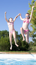 two girls jumping into pool - image by istockphoto